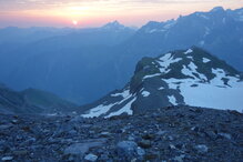 Morgensonne am Horizont über der Claridenhütte